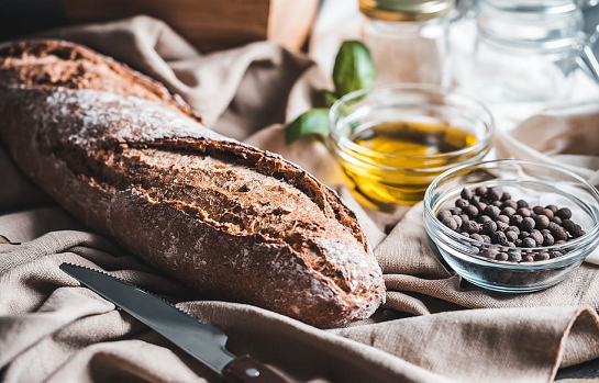 Bread, bowl of oil, on a messy table cloth
